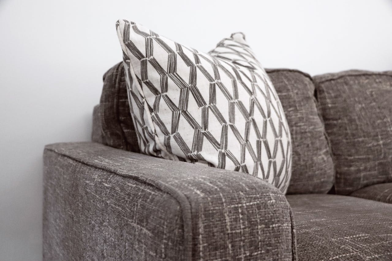 Stylish gray sofa with a patterned throw pillow adds elegance to any living space.